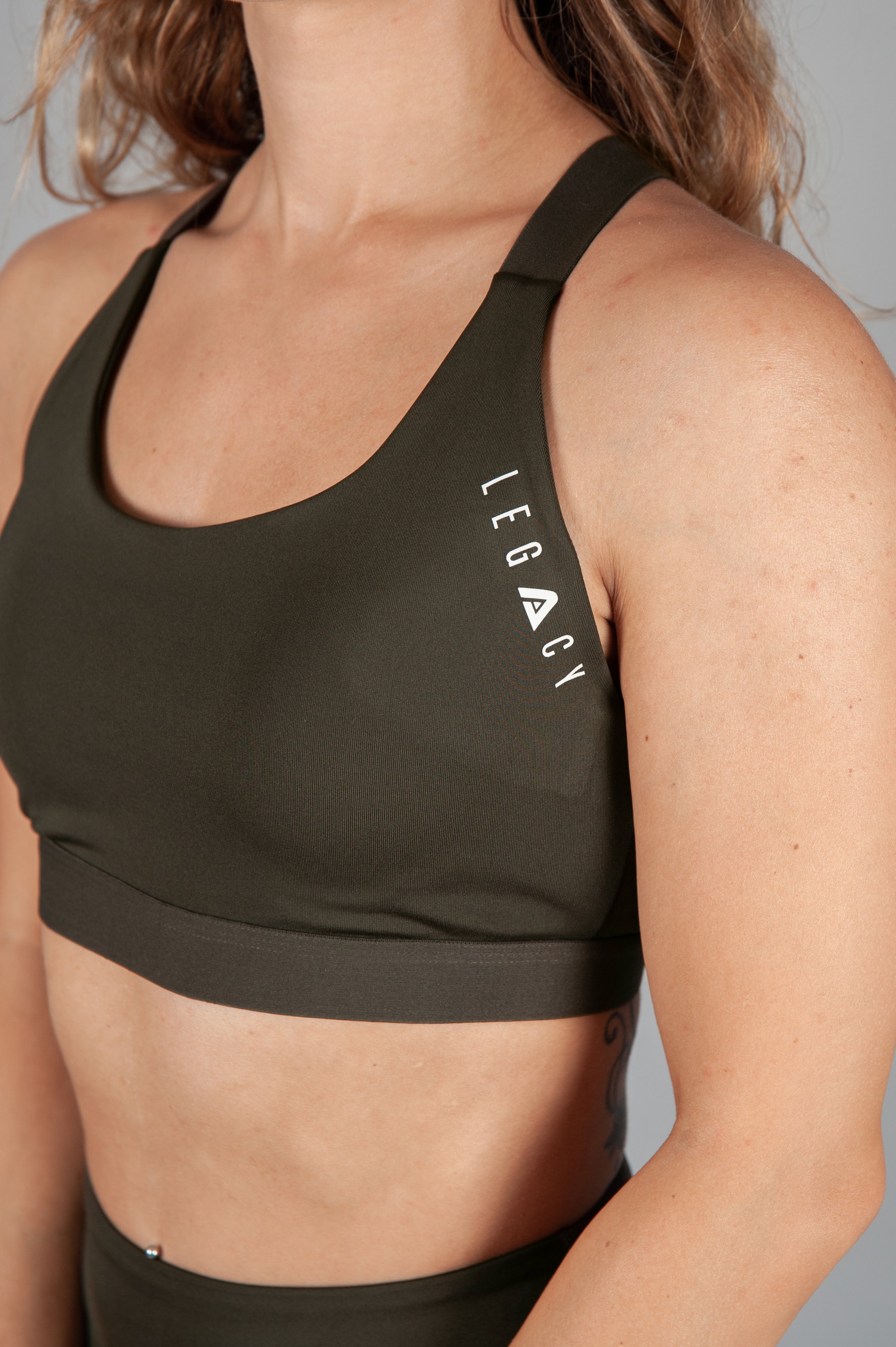 Women's olive sports bra with white Legacy logo on the side.