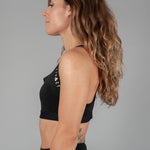 Side view of women's black sports bra with white Legacy logo on the side.