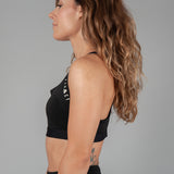Side view of women's black sports bra with white Legacy logo on the side.