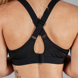 Back view of women's black sports bra with cross-over adjustable straps and clasp back.