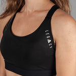 Women's black sports bra with white Legacy logo on the side.